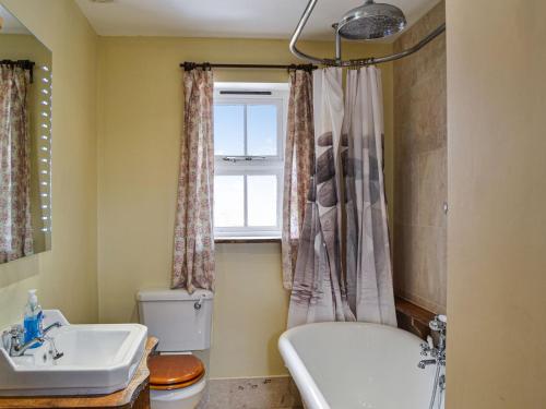 a bathroom with a tub and a toilet and a sink at Bradcar Farm Cottage in Snetterton