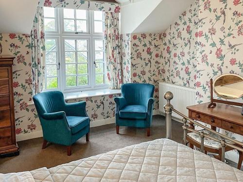 a bedroom with two chairs and a bed and a window at Sandfold Farm in Newby Bridge