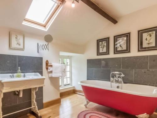 a red bath tub in a bathroom with a sink at Sandfold Farm in Newby Bridge