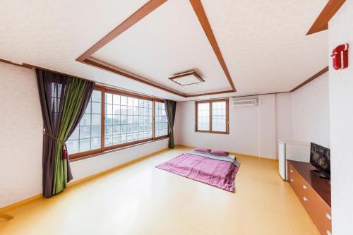 um quarto vazio com uma grande janela e uma cama em Remember Youth Hostel em Gyeongju