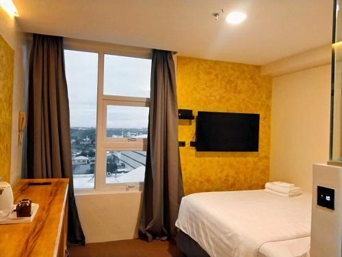 a hotel room with a bed and a window at Sempre Premier Inn - MACTAN AIRPORT HOTEL in Mactan