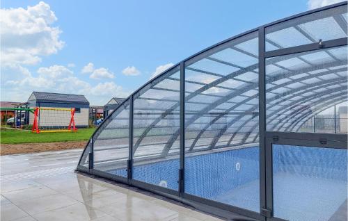 ein Glasgebäude mit einem Spielplatz im Hintergrund in der Unterkunft Cozy Home In Jezierzany With Sauna in Jezierzany