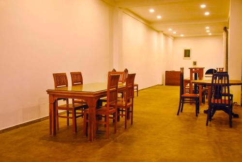 a dining room with wooden tables and chairs at Kavin Beach Hotel Hikkaduwa in Hikkaduwa