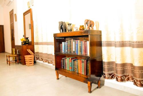 a book shelf filled with books next to a window at Kavin Beach Hotel Hikkaduwa in Hikkaduwa