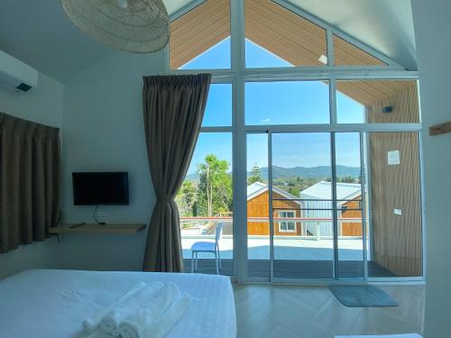 a bedroom with a bed and a large window at Serene Khaokho in Ban Khao Ya Nua