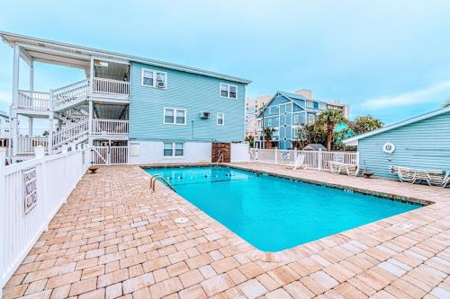 a swimming pool in front of a blue house at Seaward Escape - Cherry Grove Beach in Myrtle Beach