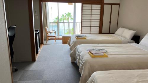 a hotel room with three beds and a balcony at Obama Onsen Hamakan Hotel in Unzen