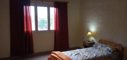 1 dormitorio con 1 cama y una ventana con cortinas rojas en Alquiler temporario Marcos en San Rafael