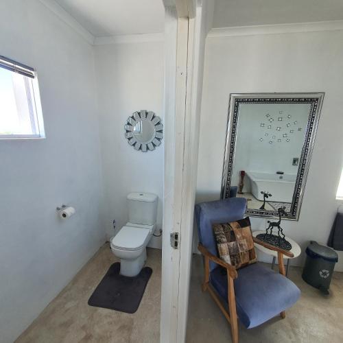 a bathroom with a toilet and a chair and a mirror at Atlantic Loft - Open plan apartment with Sea Views in Melkbosstrand
