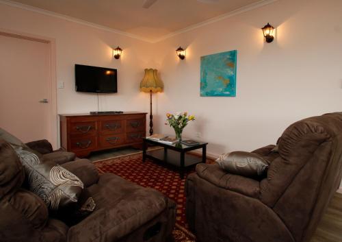 a living room with two chairs and a flat screen tv at Hill Cottage Hahndorf in Hahndorf