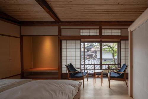 a bedroom with a bed and two chairs and a table at TANIYA in Takayama
