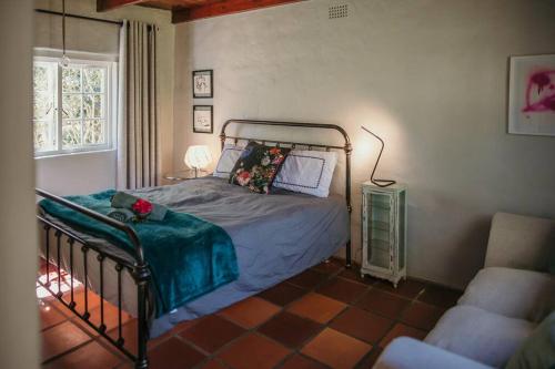 ein Schlafzimmer mit einem Bett, einem Stuhl und einem Fenster in der Unterkunft Classic Greyton Cottage for Two in Greyton