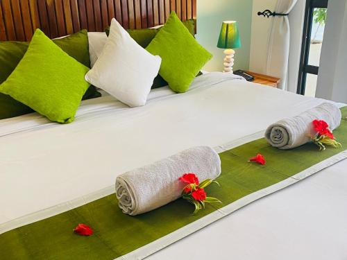 a bed with towels and red flowers on it at Cabanes Des Anges in La Digue