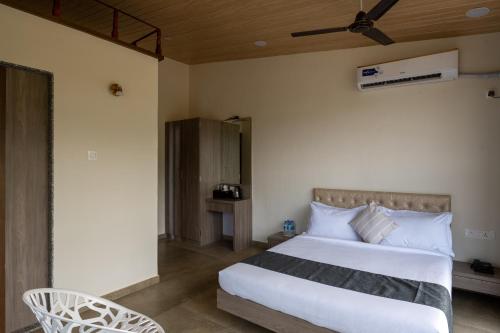 a bedroom with a large white bed and a chair at HillRock Resort & Villas, Neral-Karjat in Karjat