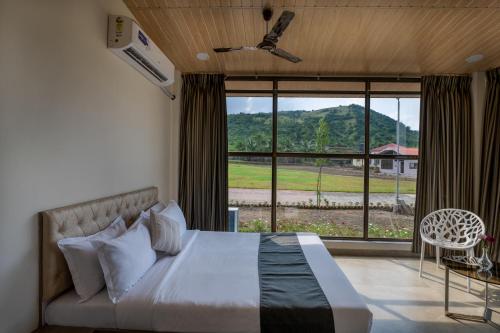 a bedroom with a bed and a large window at HillRock Resort & Villas, Neral-Karjat in Karjat