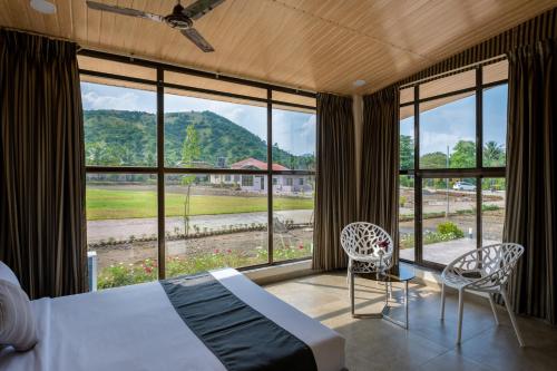 a bedroom with a bed and a large window at HillRock Resort & Villas, Neral-Karjat in Karjat