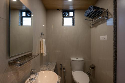 a bathroom with a toilet and a sink and a mirror at HillRock Resort & Villas, Neral-Karjat in Karjat