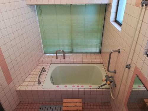 a bathroom with a bath tub with a window at House near Shimonada Station and Cat island. in Kami-nada