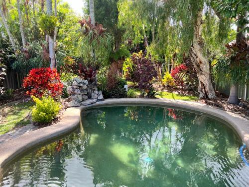 a swimming pool in a garden with trees and flowers at Comfortable Beach Home Scarborough in Scarborough