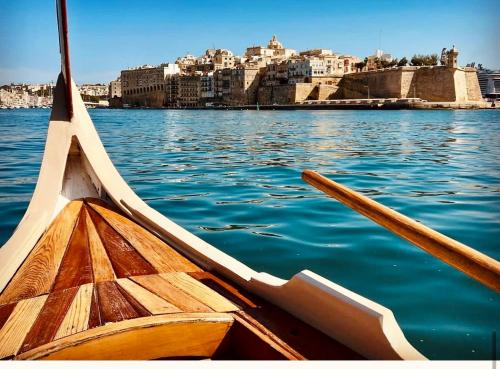 two wooden boats in the water with a city at New & unique apartment - A 5 minutes ferry to capital city of Valletta in Senglea