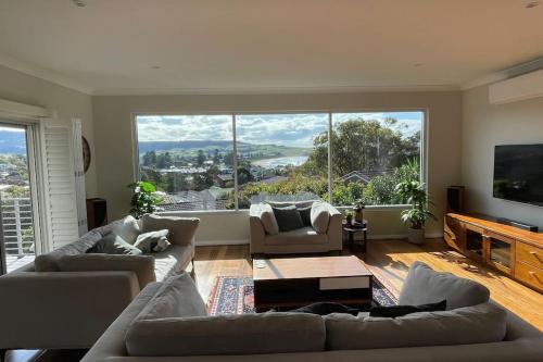 a living room with couches and a large window at Seaview at Gerringong - 4pm check out if available in Gerringong
