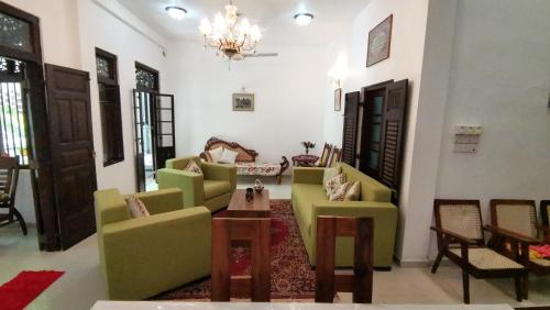 a living room with green chairs and a chandelier at Southern Comforts - Galle Fort in Galle
