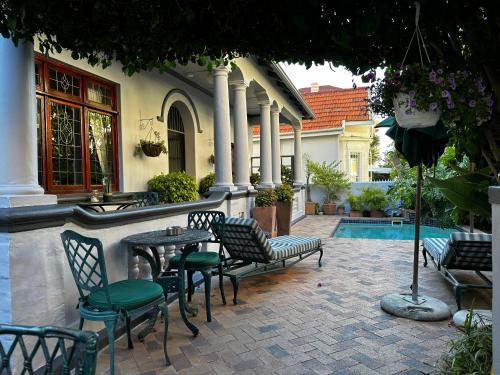 um pátio com uma mesa e cadeiras e uma piscina em Olaf's Guest House "Solar installed" em Cidade do Cabo