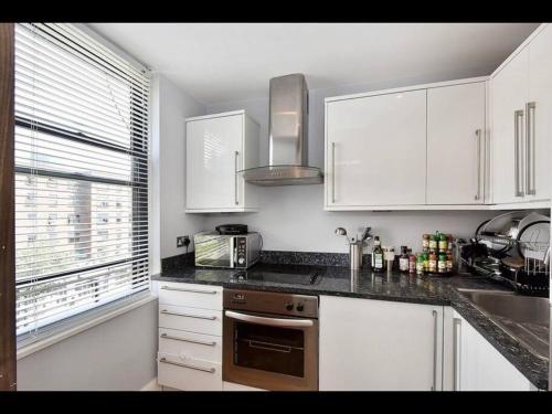a kitchen with white cabinets and a sink and a microwave at Amazing apartment central London near tube station in London