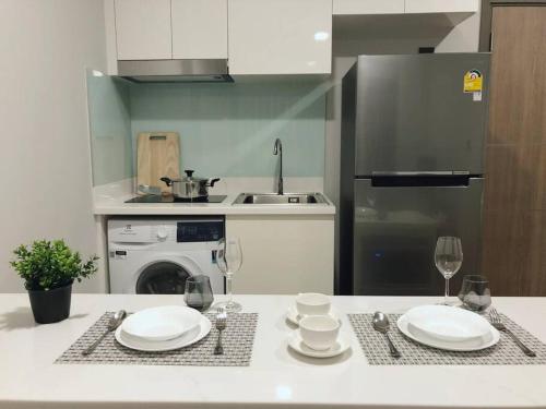 a kitchen with a table with plates and wine glasses at Modern style room with sky pool 古城边天际泳池公寓 in Chiang Mai