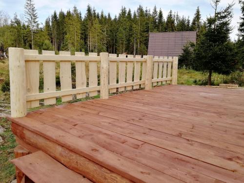 a wooden deck with a fence in a field at Chata Zuzka pod Babou horou in Oravská Polhora