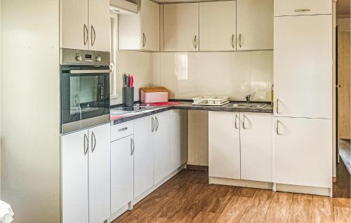 cocina con armarios blancos y suelo de madera en Nice Home In Biskupiec With Kitchen en Biskupiec