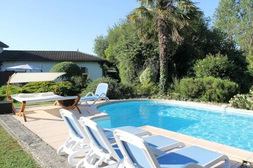 uma piscina com cadeiras brancas e uma mesa e um ecrã em Logement indépendant très calme dans propriété em Saint-Loubès