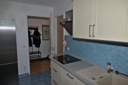 ビンツにあるFerienwohnung Rabeの青いタイルの壁、シンク付きのキッチン