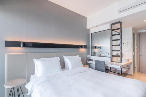 a bedroom with a large white bed and a desk at Hotel Avra by Smile hotels - Free Airport Shuttle in Rafina