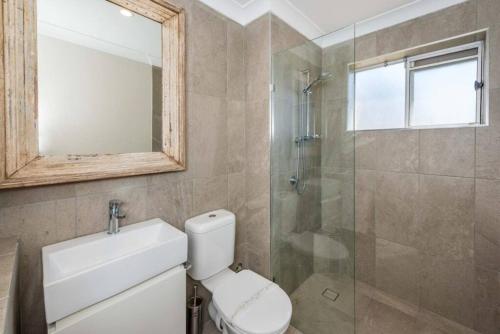 a bathroom with a toilet and a glass shower at Sparkling water views over Shoal Bay beach in Shoal Bay