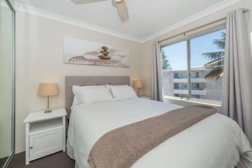 a white bedroom with a large bed and a window at Sparkling water views over Shoal Bay beach in Shoal Bay