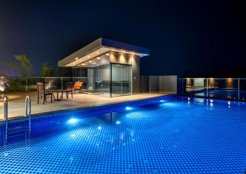 a swimming pool in front of a house at night at Crystal Suites in Badagara