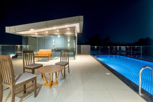 a patio with a table and chairs next to a swimming pool at Crystal Suites in Badagara