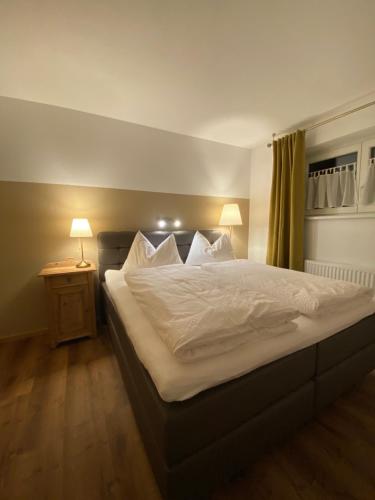 um quarto com uma cama grande com lençóis brancos e um candeeiro em Apartment Emma em Mayrhofen
