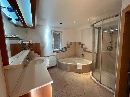 a bathroom with a tub and a sink and a shower at Woodyard in Piesendorf