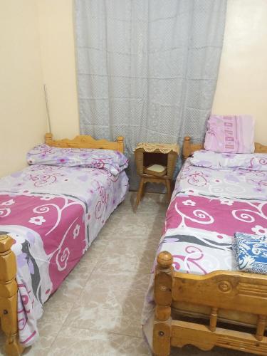 a bedroom with two beds and a chair at HORUS Nubian Guest House in Aswan