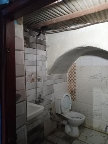 a dirty bathroom with a toilet and a sink at HORUS Nubian Guest House in Aswan