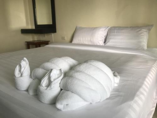 Una cama blanca con almohadas blancas. en Parisia House, en Khao Lak