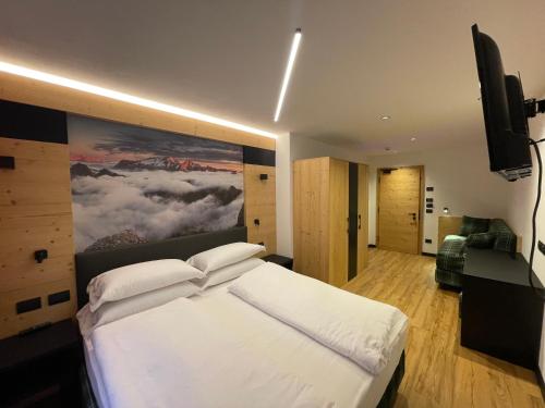 カナツェーイにあるAlbergo Garni Edy (B&B)の白いベッド1台付きのベッドルーム1室(壁に絵画付)