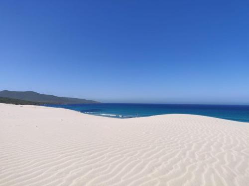 a white sand dune with the ocean in the background at Casa Nonno Remo in Porto Pino