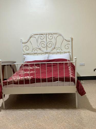 ein weißes Bett mit einer roten Decke und einem Tisch in der Unterkunft Green Haven in Mbale