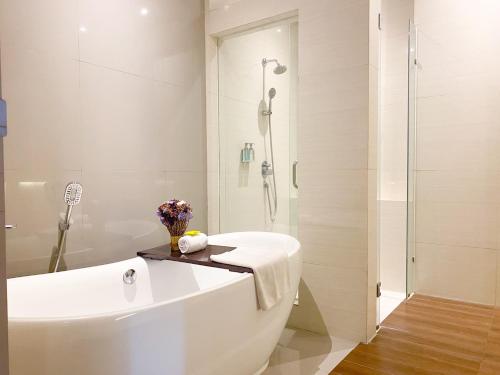 a white bathroom with a tub and a shower at Bromo Park Hotel Probolinggo in Probolinggo