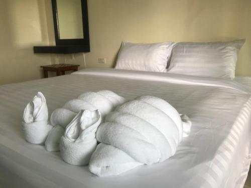 ein weißes Bett mit weißen Kissen darauf in der Unterkunft Parisia House in Khao Lak