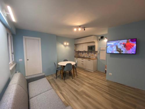 ein Wohnzimmer mit einem Tisch und einem TV an der Wand in der Unterkunft Sendy Home Roccaraso 2 in Roccaraso