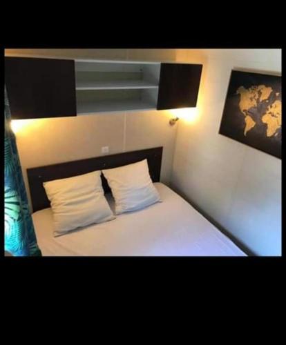 une chambre avec un lit avec des draps blancs et des oreillers dans l'établissement Mobil home 4-6 personnes bord de mer Argeles sur mer camping équinoxe, à Argelès-sur-Mer